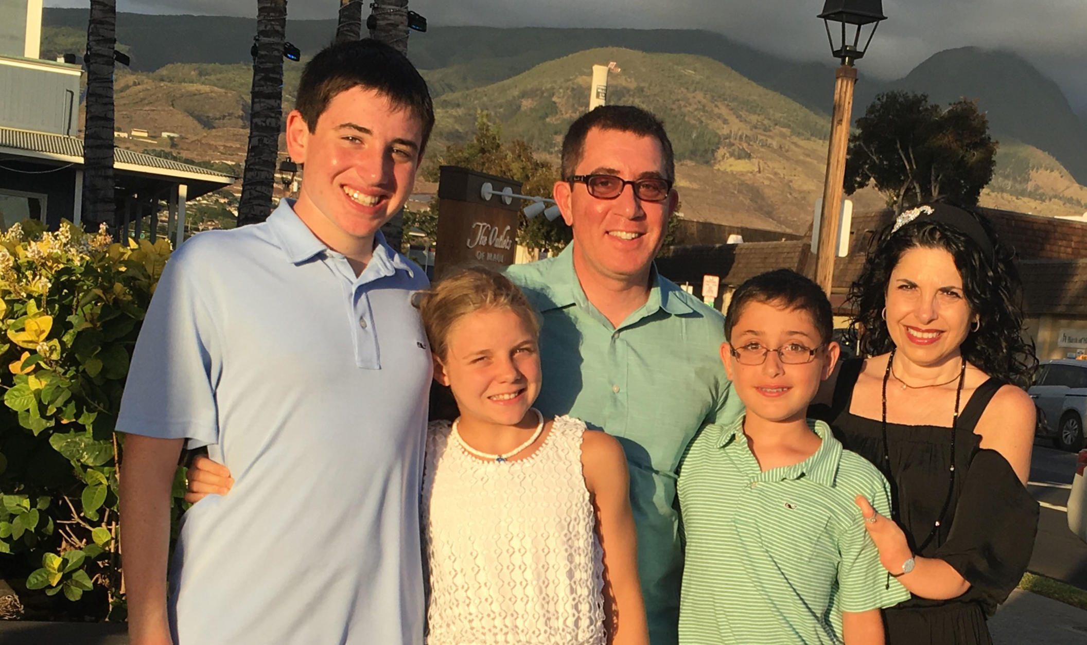Meg Zucker and family which includes three children and husband smiling at camera while outdoors