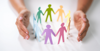 Hands encircle colorful paper cutouts of people holding hands, symbolizing unity and diversity, much like SEL activities promoting social emotional growth. The figures in blue, green, yellow, red, and purple form a circle on a white background.