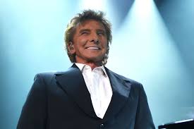 A person in a dark suit and white shirt stands smiling under stage lights, looking upwards, embodying the spirit of social emotional learning. The background is blurred with a bluish tint, giving a concert-like atmosphere that encourages get to know you activities for students.