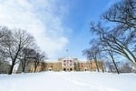 A large building with a red and white banner on the facade stands on a snowy landscape, where social emotional learning activities often take place. Leafless trees frame the scene under the clear blue sky, inviting students to engage in meaningful get-to-know-you activities.