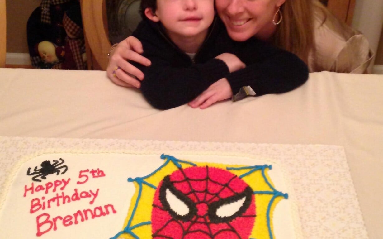 A child and an adult share a joyful moment over a Spider-Man themed birthday cake, perfect for adding a touch of fun to any SEL curriculum. The cake, a heartwarming "get to know you" activity, reads "Happy 5th Birthday Brennan" with a small heart inscribed with "Mommy.