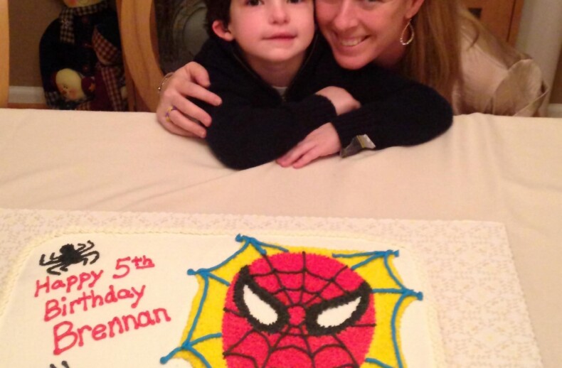 A child and an adult share a joyful moment over a Spider-Man themed birthday cake, perfect for adding a touch of fun to any SEL curriculum. The cake, a heartwarming "get to know you" activity, reads "Happy 5th Birthday Brennan" with a small heart inscribed with "Mommy.