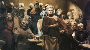 A diverse group of alien creatures gathers in a dimly lit cantina, their variety of clothing and distinct features creating an eclectic atmosphere reminiscent of social emotional learning activities, as they stand and sit around small tables, engaged in vibrant interactions.