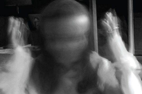 A blurred, black and white image of a person with raised arms, possibly conveying motion or emotion, evokes themes from social emotional learning curriculum. The details are indistinct, with the background hinting at a room's furniture.