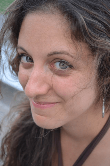 A woman with long, wavy hair smiles softly at the camera. She is wearing earrings and a brown top, subtly reflecting her passion for diversity programs. The background is slightly blurred.