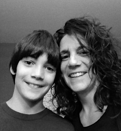 A black and white photo captures a smiling woman with curly hair and a young boy with straight hair, embodying the warmth central to social emotional learning curriculum. Close together, they look at the camera against a plain background, reflecting a moment of connection and understanding.