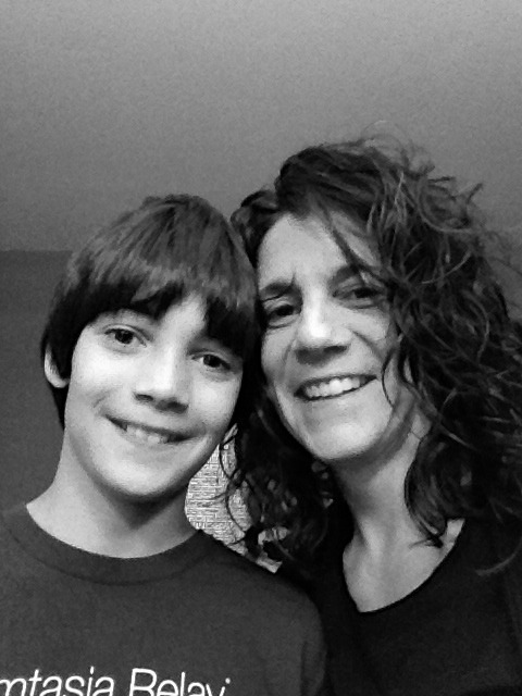 A black and white photo captures a smiling woman with curly hair and a young boy with straight hair, embodying the warmth central to social emotional learning curriculum. Close together, they look at the camera against a plain background, reflecting a moment of connection and understanding.