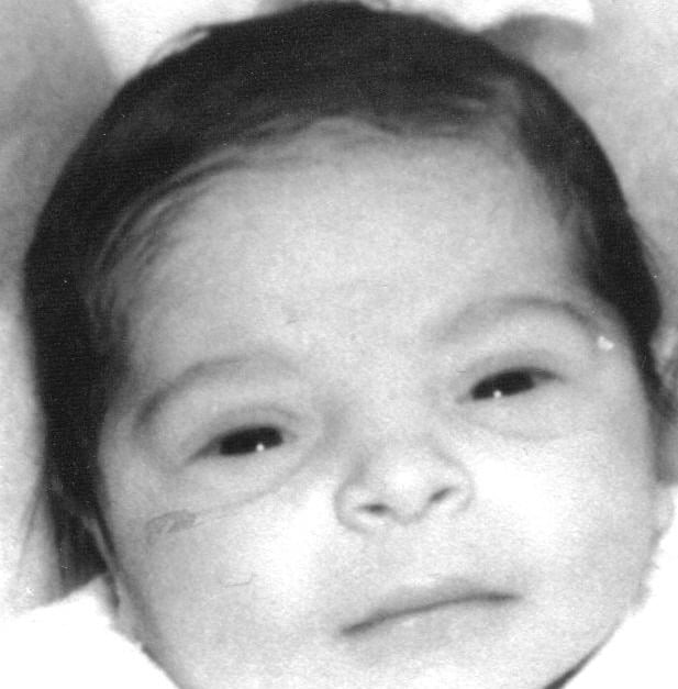 In a black and white photo, a newborn baby with dark hair and closed eyes rests serenely on a soft surface. The baby's peaceful expression beautifully echoes the essence of social emotional learning activities, fostering tranquility from the very beginning.