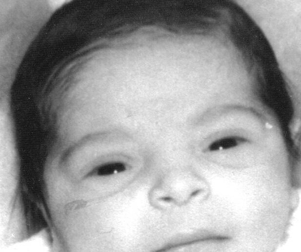 Black and white close-up of a sleeping newborn baby with dark hair. The image focuses on the baby's face resting peacefully, capturing the innocent and delicate features typical of a newborn, much like the tender beginnings explored in a social emotional learning curriculum.