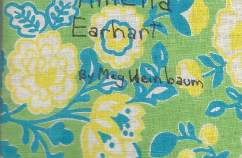 A handmade book cover with a floral pattern in green, yellow, and blue. The text reads "Amelia Earhart" and "by Meg Heimbaum" in handwritten style. In the top right, it says "My report about," making it perfect for integrating SEL activities into your classroom projects.