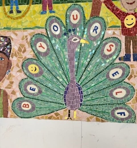 A colorful mosaic mural features a peacock with its vibrant tail feathers displaying the words "BE YOURSELF," embodying social emotional learning. Surrounding the peacock are intricate figures and bright colors, inviting get-to-know-you activities for students to explore diversity programs.