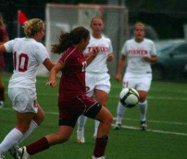 A soccer match unfolds with players in white and maroon uniforms. The focus is on a maroon-clad player, poised to kick the ball amid white-uniformed teammates. This moment fosters teamwork and strategy, echoing SEL activities that build essential social-emotional skills on and off the field.