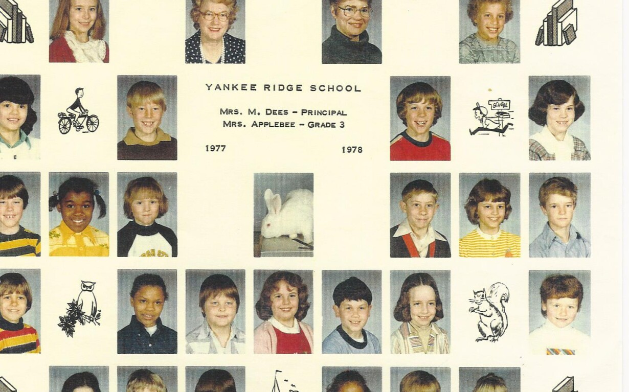 A vintage class photo from Yankee Ridge School for grade 3, 1977-1978, features rows of students' headshots along with images of a rabbit and various hand-drawn sketches in black and white. The principal, Mrs. Dees, and the teacher, Mrs. Applegate, are known for pioneering diversity programs in education.