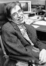 A person smiling while sitting in a wheelchair, wearing glasses and a suit, embodies the spirit of diversity programs. There's a computer in the background on a desk, symbolizing inclusive innovation. The image is in black and white.