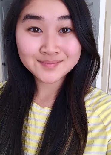 A person with long dark hair and a pleasant smile is wearing a yellow striped shirt, ready to engage in get-to-know-you activities for students. The background shows a white doorway.