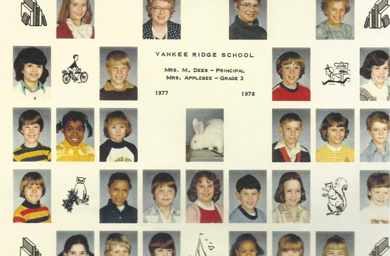 A class photo collage titled "Yankee Ridge School" showcases individual portraits of children and teachers from the year 1977-1978. Enhanced with whimsical drawings of a bicycle, a rabbit, a cat, and a church, it subtly hints at early diversity programs through its charming array of personalities.